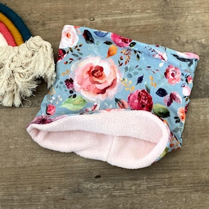 Könnte beinhalten: Ein blauer und rosa Fleece-Halswärmer mit einem Blumendruck mit rosa, roten und weißen Rosen. Der Halswärmer ist aus weichem Fleece gefertigt und perfekt, um sich im Winter warm zu halten.