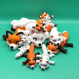 May include: A group of nine small, hand-painted fox figurines in various poses. The foxes are made of white and orange ceramic and have black eyes and noses. Some of the foxes are lying down, while others are standing up. The foxes are all different sizes and shapes.