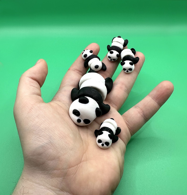 Puede incluir: Cinco peque&ntilde;as figuritas de panda negras y blancas, hechas de arcilla polim&eacute;rica, se muestran en la mano de una persona. Los pandas est&aacute;n en varias poses, incluyendo dormir y sentarse.