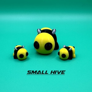 May include: Three yellow and black bee figurines. The largest bee is in the center and the two smaller bees are on either side. The bees have black eyes and silver antennae.