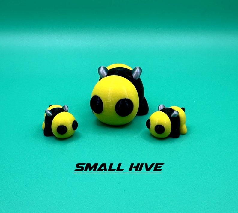 May include: Three yellow and black bee figurines. The largest bee is in the center and the two smaller bees are on either side. The bees have black eyes and silver antennae.