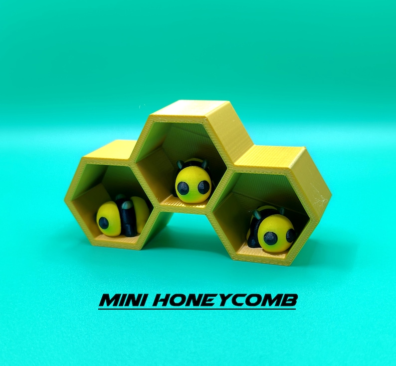 May include: A yellow honeycomb-shaped shelf with three compartments, each containing a small yellow and black bee figurine. The shelf is labeled "MINI HONEYCOMB".