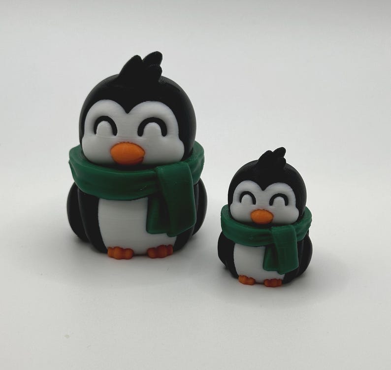 Op de afbeelding: Twee pingu&iuml;nbeeldjes. De pingu&iuml;ns zijn zwart en wit met oranje snavels en voeten. Elke pingu&iuml;n draagt een groene sjaal. De ene pingu&iuml;n is groter dan de andere.