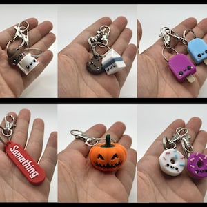 Pu&ograve; includere: Una collezione di portachiavi fatti a mano con vari design. Include un marshmallow, un biscotto e una casa, due portachiavi a forma di ghiacciolo, un'etichetta rossa con la parola "Something", una zucca e due ciambelle. Ogni portachiavi ha un fermaglio argentato.
