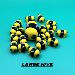 May include: A large group of yellow and black bee figurines with silver accents. The bees are arranged in a cluster, resembling a beehive. The figurines are made of plastic and have a glossy finish.