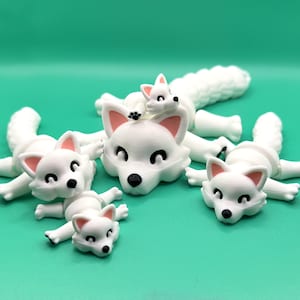 May include: Four white fox figurines with pink noses and black eyes. The foxes are in various poses, including lying down and sitting up. The figurines are made of a smooth, white material.
