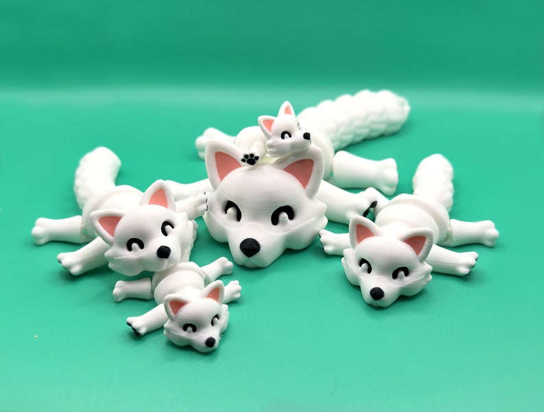 May include: Four white fox figurines with pink noses and black eyes. The foxes are in various poses, including lying down and sitting up. The figurines are made of a smooth, white material.