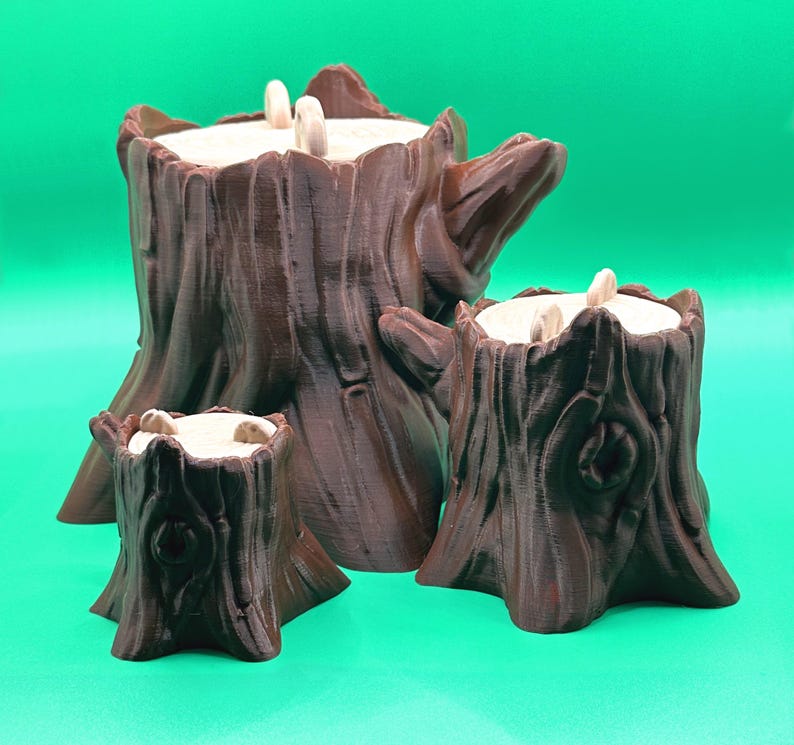May include: Three brown tree stump-shaped candle holders of varying sizes. Each has a textured, bark-like exterior and a light-colored interior with three white candles. The candle holders are arranged against a solid green background.
