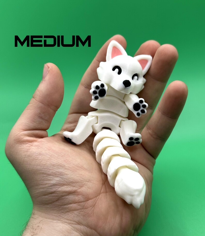 May include: White articulated toy fox with black paw prints. The toy is posed sitting with its tail curled up. The toy is about 5 inches tall.