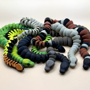 May include: Several articulated snake toys in shades of green, black, brown, and grey. The toys are constructed from segmented parts, enabling them to flex and move. The snakes feature detailed heads.