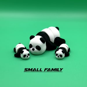 Puede incluir: Una peque&ntilde;a familia de tres osos panda negros y blancos. La madre panda est&aacute; acostada con sus dos cachorros a su lado.
