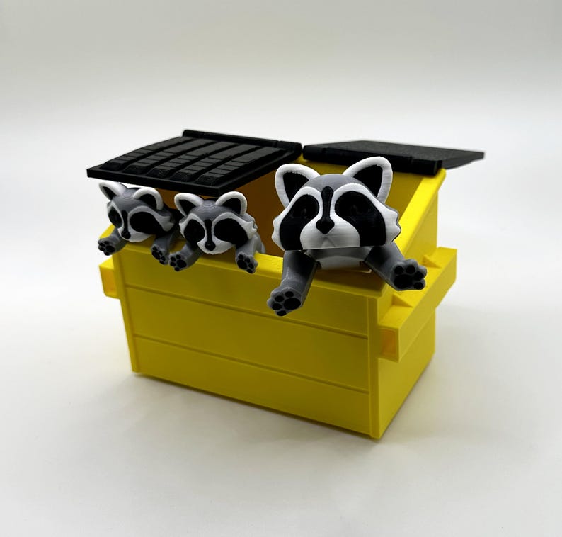 May include: A yellow toy dumpster with a black lid and three gray and white raccoon figurines peeking over the edge.