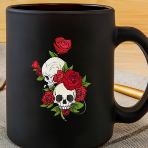 May include: Black ceramic coffee mug with a graphic of two white skulls surrounded by red roses.