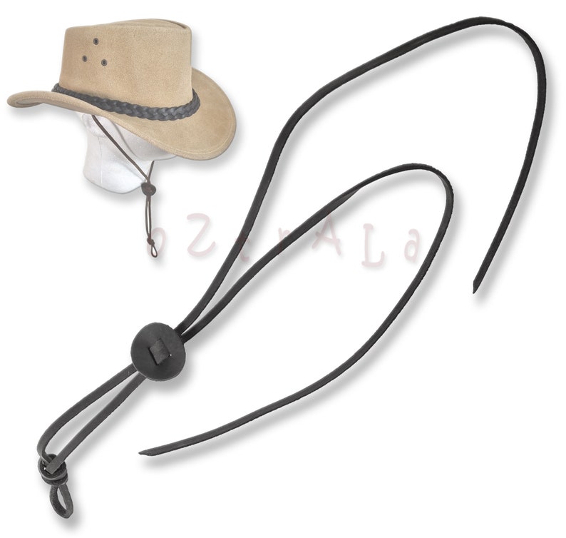 May include: A tan cowboy hat with a black leather chin strap. The strap has a black leather button and a loop at the end.