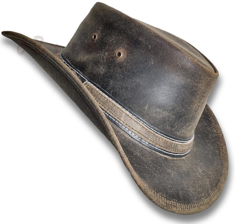 Puede incluir: Sombrero de vaquero de cuero marr&oacute;n desgastado con ala ancha. El sombrero presenta una banda decorativa con costuras blancas y dos peque&ntilde;os orificios de ventilaci&oacute;n en la corona. Dise&ntilde;ado para la protecci&oacute;n solar y actividades al aire libre.
