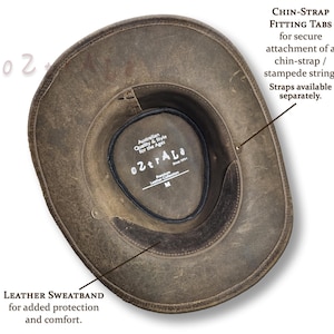 Puede incluir: Sombrero de cuero marr&oacute;n desgastado con una banda de sudoraci&oacute;n de cuero y pesta&ntilde;as de ajuste para la barbilla. El sombrero tiene el texto "o2traLa" y "Australian Quality & Style for the Ages" en el interior. Talla M.