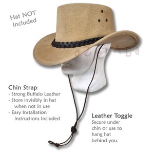 May include: A brown leather cowboy hat with a braided leather band. The hat is on a white mannequin head. The hat has a chin strap with a leather toggle. The text "Hat NOT Included" is in the top left corner of the image. The text "Chin Strap" and "Leather Toggle" are in the bottom left and right corners of the image, respectively. The text describes the features of the chin strap and leather toggle.