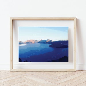 May include: A framed photograph of a mountain lake with a blue and purple color scheme. The lake is surrounded by mountains and trees. The photo is in a light wood frame.