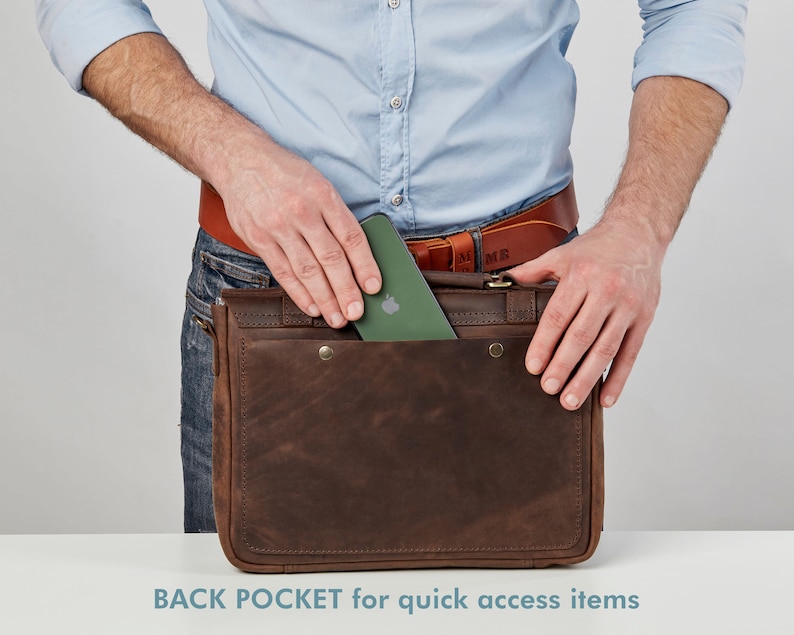 May include: A brown leather messenger bag with a back pocket for quick access items. A green phone is being placed in the pocket.