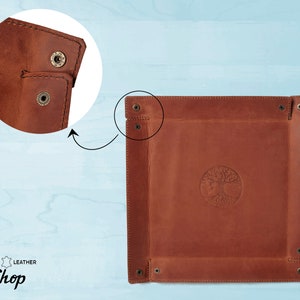 May include: A brown leather tray with a tree of life design embossed in the center. The tray has four brass rivets on each corner and is made of high-quality leather.