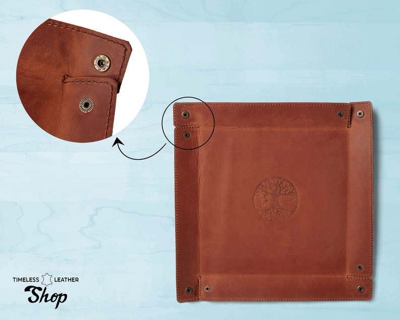 May include: A brown leather tray with a tree of life design embossed in the center. The tray has four brass rivets on each corner and is made of high-quality leather.