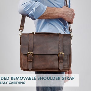 May include: A brown leather messenger bag with a padded, removable shoulder strap. The bag has two buckles on the front and a brass clasp.