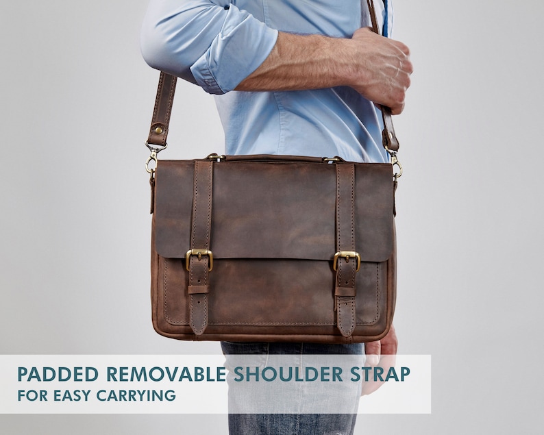 May include: A brown leather messenger bag with a padded, removable shoulder strap. The bag has two buckles on the front and a brass clasp.