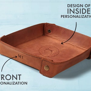 May include: A brown leather tray with a tree design on the inside and the initials "MT" on the front.
