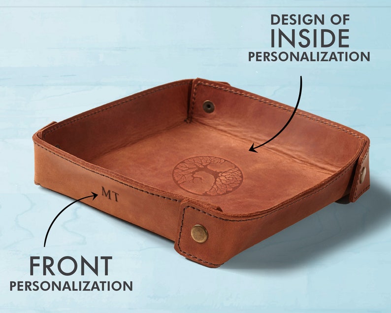 May include: A brown leather tray with a tree design on the inside and the initials "MT" on the front.