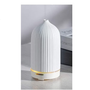 May include: White ceramic essential oil diffuser with a ribbed design and a light-up base.