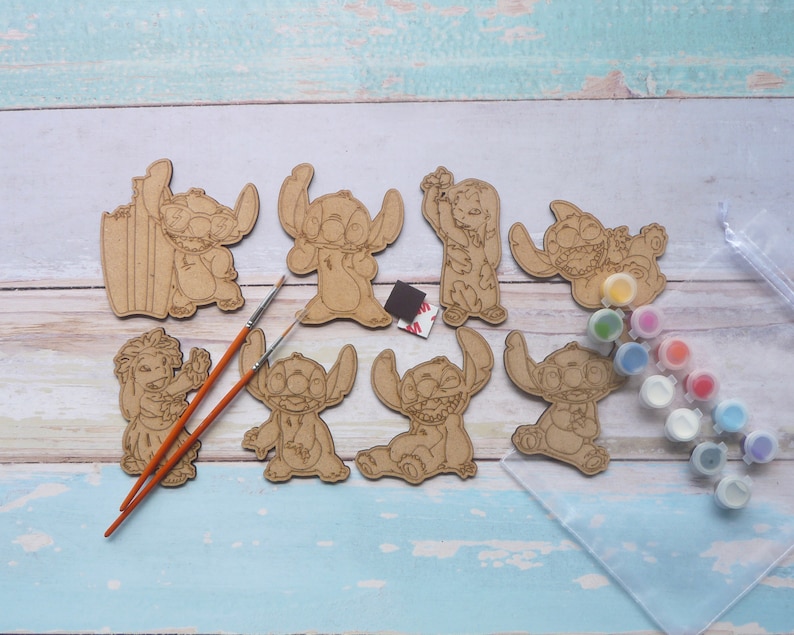 K&ouml;nnte beinhalten: Ein Set mit sechs unfertigen Holz-Ausschnitten von Stitch aus Lilo & Stitch, bereit zum Bemalen. Das Set enth&auml;lt Pinsel und einen Satz Acrylfarben in verschiedenen Farben.