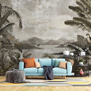 May include: A light blue sofa with a gray throw blanket and orange and beige throw pillows sits in front of a wall mural depicting a tropical landscape with palm trees, mountains, and a lake.