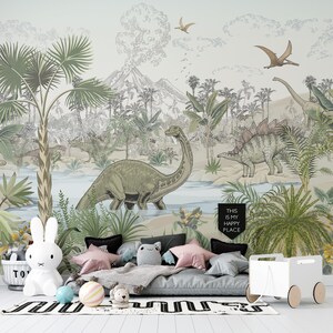 May include: A children's bedroom with a mural featuring a jungle scene with dinosaurs, palm trees, and a volcano. The mural is painted in shades of green, brown, and blue. A gray futon with pillows and a white toy chest are in front of the mural. The text "This is my happy place" is written on a black banner hanging from the ceiling.