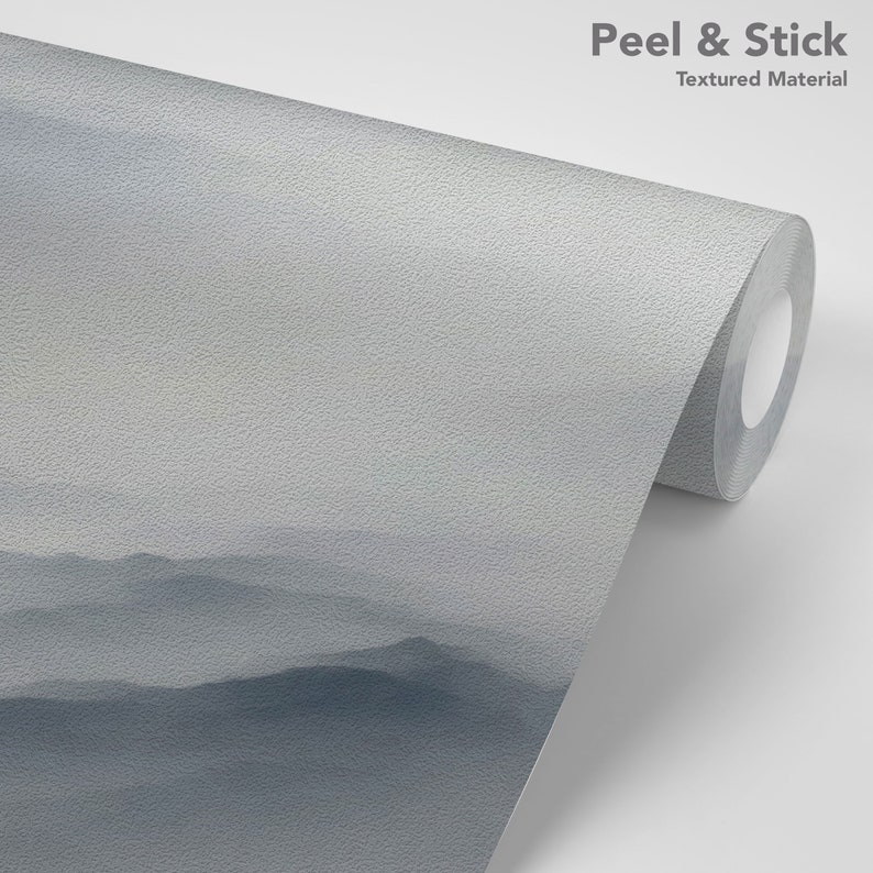 May include: A roll of peel and stick wallpaper with a textured surface. The wallpaper features a misty mountain landscape in shades of blue and gray.