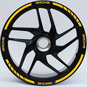 Peut inclure: Une jante noire avec une bande de course jaune et le mot "RACING" répété autour de la jante.