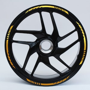 Peut inclure: Une jante de roue de moto noire avec une bande dorée et un motif noir et or.