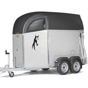 Op de afbeelding: Een zilveren paardenwagen met een zwart dak en een paardenkoplogo. De wagen heeft een enkele deur aan de linkerkant en een laadklep aan de rechterkant. De wagen heeft twee wielen aan de achterkant en één wiel aan de voorkant.