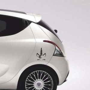 Può includere: Un'auto bianca con un adesivo di unicorno nero sul retro.