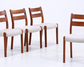 Könnte beinhalten: Vier Holzstühle mit hell gepolsterten Sitzen. Die Stühle haben ein schlichtes, modernes Design aus der Mitte des Jahrhunderts mit einem warmen, rötlich-braunen Finish. Die Stühle sind in einer Gruppe angeordnet.