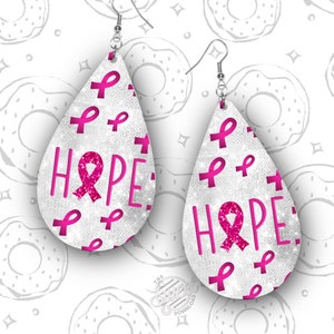 May include: A pair of silver teardrop-shaped earrings with a white glitter background and pink ribbon accents. The earrings feature the word "HOPE" with a pink ribbon in the center of the word.
