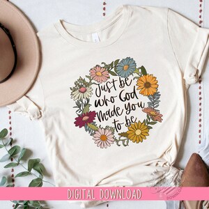 May include: A white t-shirt with a floral wreath design and the text "Just be who God made you to be".