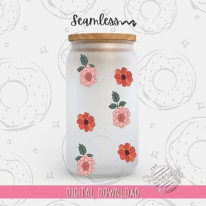 May include: A white glass jar with a wooden lid, decorated with five floral stickers. The stickers feature pink and orange flowers with green leaves. The jar is on a white background with a pattern of donuts.