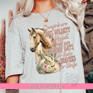 May include: A gray t-shirt with a graphic design of a horse, cactus, and a cowboy hat. The text on the shirt reads "Cowgirls are God's Wildest Angels. They have Cowboy Hats for halos & Horses for wings."