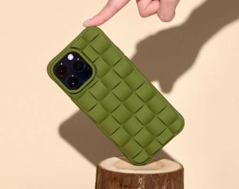 May include: Olive green phone case with a woven texture, held by a hand. The case is displayed on a tree stump with moss and flowers. The text "Ninetydegree" is written in cursive at the bottom.