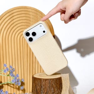 May include: A cream-coloured smartphone case with a textured lizard-skin pattern. The case features a rectangular camera cutout with three circular lens openings and a flash. The word Ninetydegree is printed in a cursive script at the bottom.