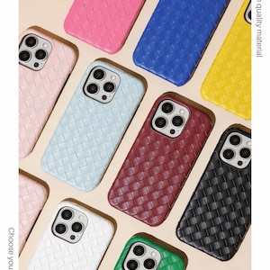 Könnte beinhalten: Eine Auswahl an gewebten iPhone-Hüllen in verschiedenen Farben, darunter Rosa, Blau, Gelb und Schwarz. Die Hüllen weisen ein strukturiertes, korbgeflechtartiges Design auf und sind auf einem neutralen Hintergrund angeordnet. Der Text "Woven iPhone case" ist sichtbar.