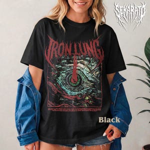 May include: Black t-shirt featuring the text "IRON LUNG" in a red, gothic font above a detailed eye graphic with green, red, and blue hues. The shirt also has the word "Black" printed on it.
