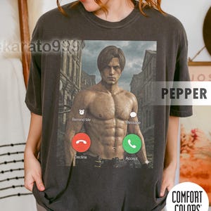 Peut inclure: T-shirt gris foncé avec un graphisme d'un homme musclé dans un cadre urbain délabré, encadré comme un écran d'appel téléphonique. Comprend les mots "Remind Me", "Message", et les boutons "Decline" et "Accept". Le mot "PEPPER" est imprimé sur le t-shirt.