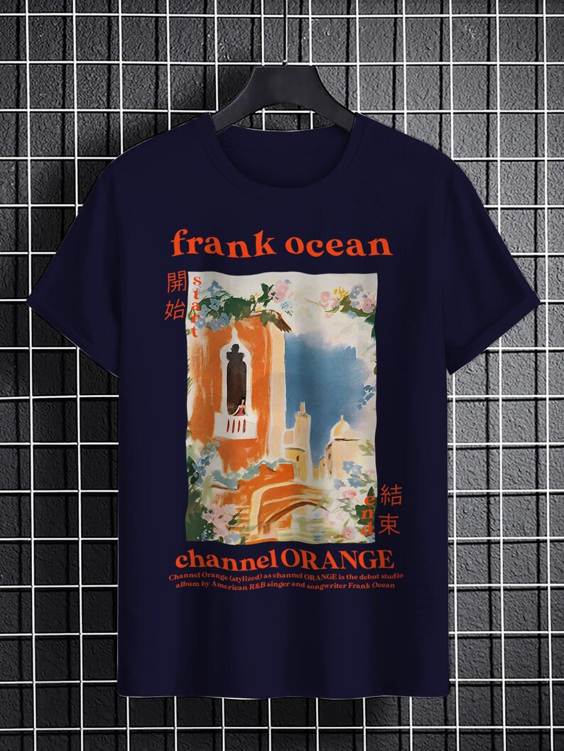 May include: A navy blue t-shirt with a graphic print of a building with a balcony and flowers. The text "frank ocean" and "channel ORANGE" is printed in red on the shirt. The text "開始" and "結束" is printed in red on the shirt in Japanese characters.