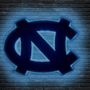 Puede incluir: Un letrero de ne&oacute;n azul y negro con las letras "NC" en una fuente estilizada. El letrero est&aacute; iluminado con una luz azul brillante.